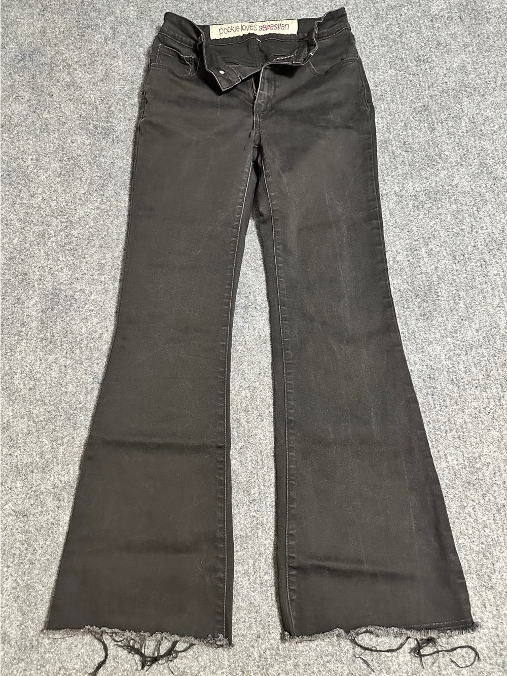 The black flare jeans in the image feature a distinctive white waistband tag